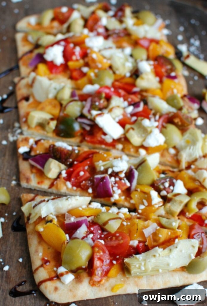 Mediterranean Flatbread is a quick and easy vegetarian meal made on your favorite flatbread or naan. Your favorite Mediterranean flavors of hummus, olives, artichokes, roasted peppers, feta cheese, tomatoes, red onion and balsamic glaze create a colorful, flavor packed appetizer or meal. 