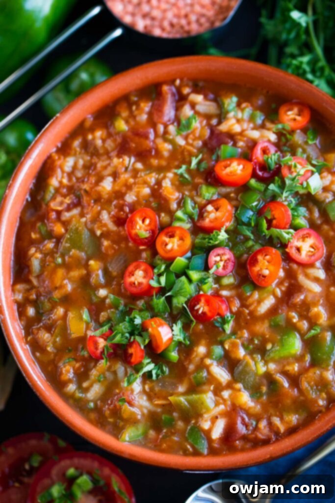 Vegan Stuffed Pepper Soup - A vibrant bowl of vegetarian stuffed pepper soup, rich with tomatoes, rice, and bell peppers, topped with fresh herbs.