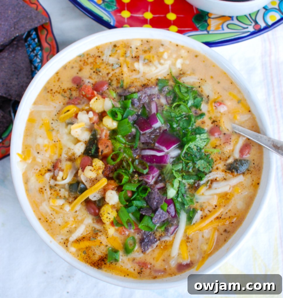 Fiesta Bean Pozole 3 A close-up of a bowl of Zesty Bean Pozole Soup with a spoon, highlighting the rich textures and colors of red beans, hominy, and melted cheese, ready to be enjoyed.