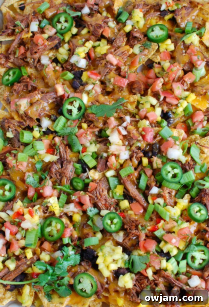 Beef nachos freshly baked on a baking sheet, ready to be topped.