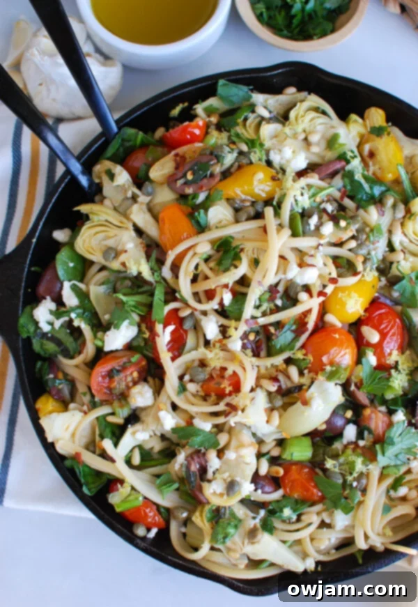 Sun-Kissed Mediterranean Pasta 4 Mediterranean Pasta being prepared in a black skillet with olive oil, garlic, and cherry tomatoes, before adding other ingredients.