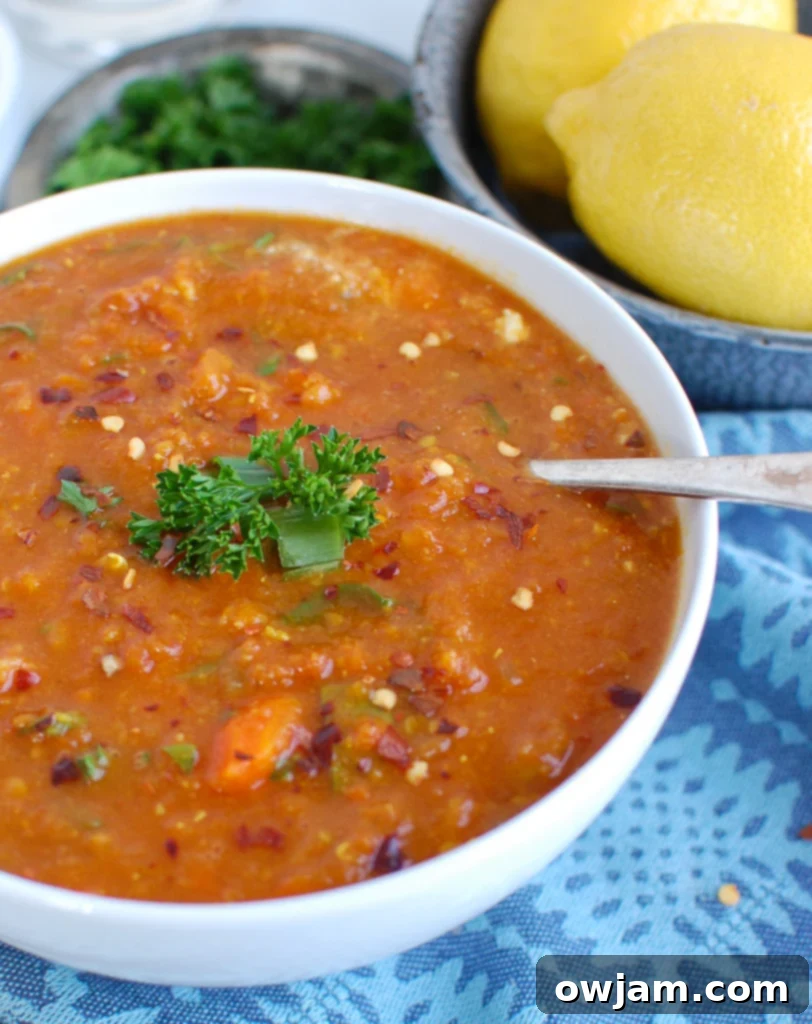 A close-up of a white bowl filled with Slow Cooker Lentil Soup, showing the blend of vegetables and lentils.