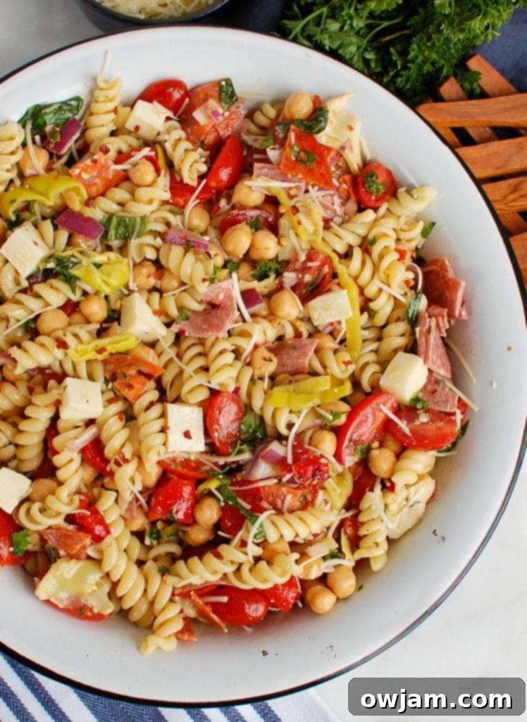 Italian Pasta Salad in a white bowl with wooden serving utensils