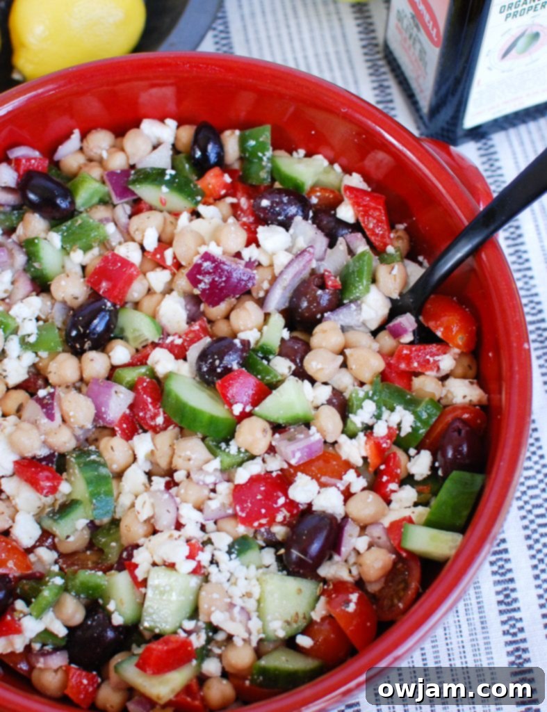 Vibrant Greek Chickpea Salad in a red bowl, perfect for picnics and meal prep.