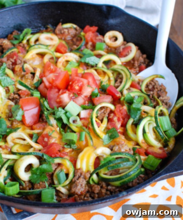 Close-up view of Mexican Zucchini Skillet, highlighting the texture of the spiralized zucchini noodles perfectly mixed with seasoned ground beef and melted cheese, ready to be served.