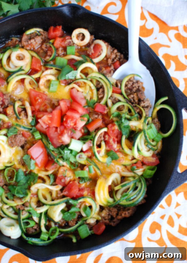 Overhead view of a vibrant Mexican Zucchini Skillet, beautifully garnished with fresh cilantro, bright diced tomatoes, and crisp green onions, ready for serving.