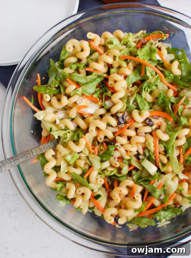 Far East Fusion Pasta Salad 3 Close-up of Asian Pasta Salad with a serving spoon, highlighting the ingredients.