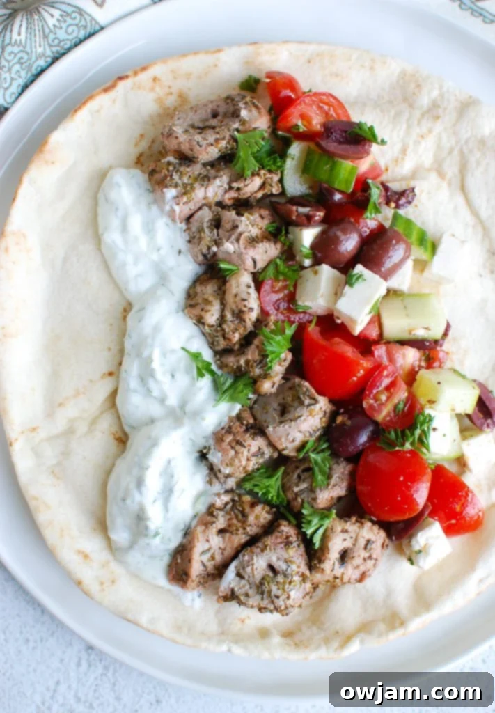 Close-up of grilled Pork Souvlaki skewers with a side of creamy Tzatziki on a plate, ready to be served.