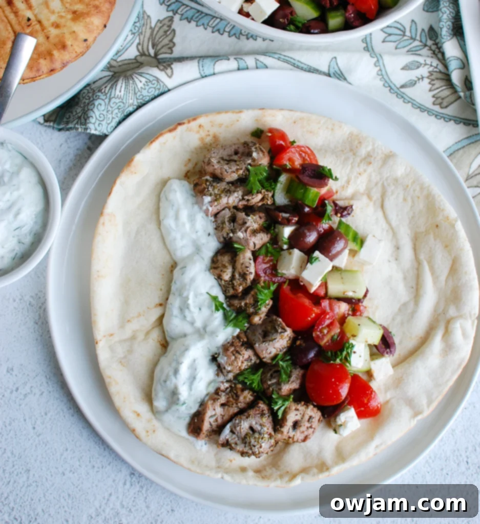 Platter of grilled Pork Souvlaki skewers, fresh Greek salad, and creamy Tzatziki sauce, highlighting the colorful ingredients.