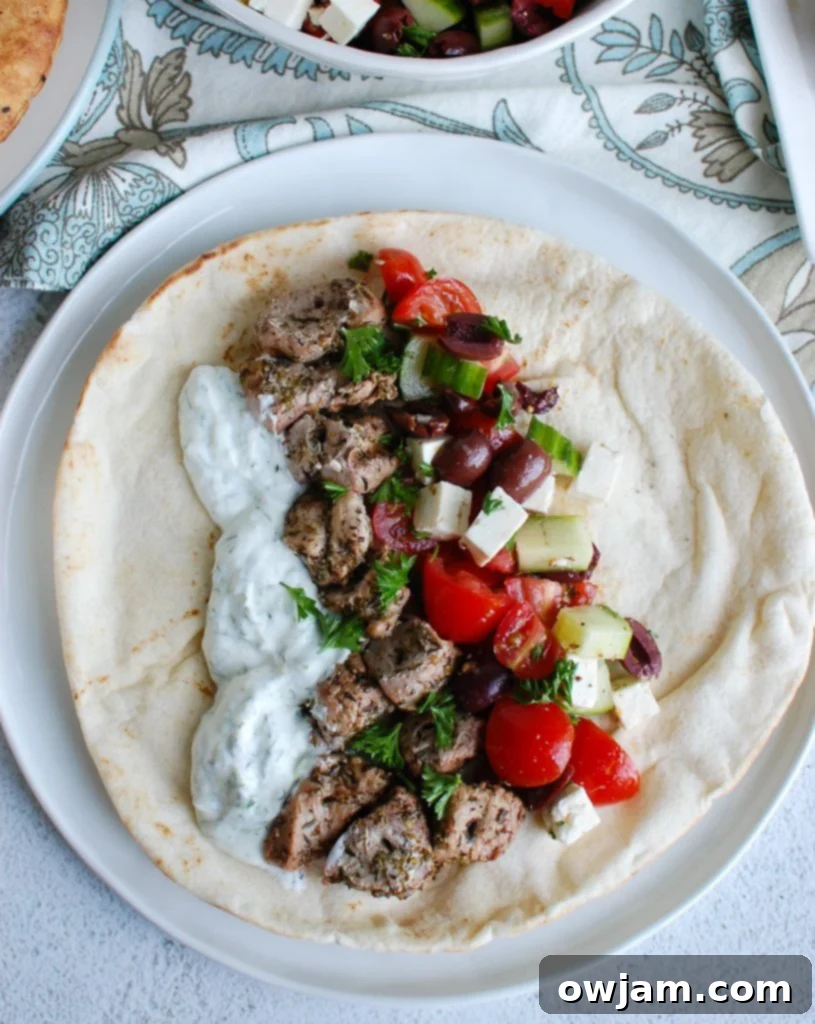 Pork Souvlaki skewers arranged on a platter with a vibrant Greek salad and a bowl of fresh Tzatziki, showcasing a complete meal.