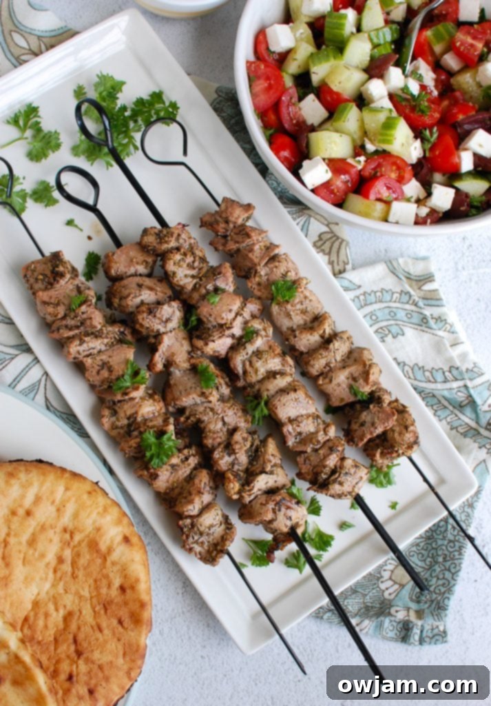 An inviting platter featuring Pork Souvlaki, fresh Tzatziki, and a colorful Greek salad, set for a summer gathering.