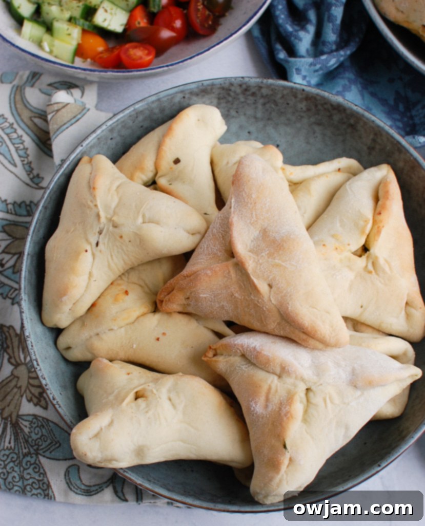Freshly baked Golden triangle-shaped Spinach Fatayer pastries in a rustic bowl, ready to serve.