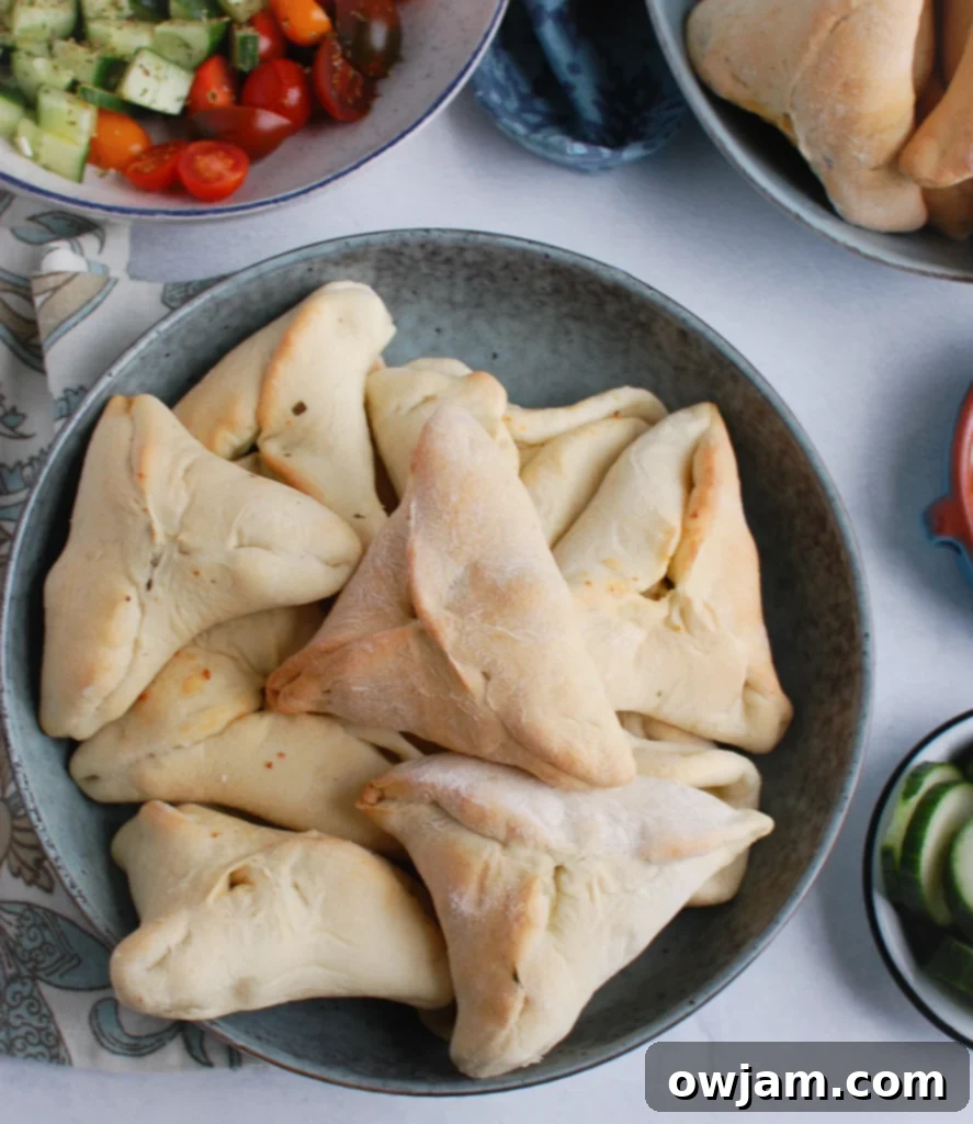 Unbaked triangular dough pastries filled with spinach and cheese, arranged in a small rustic bowl.