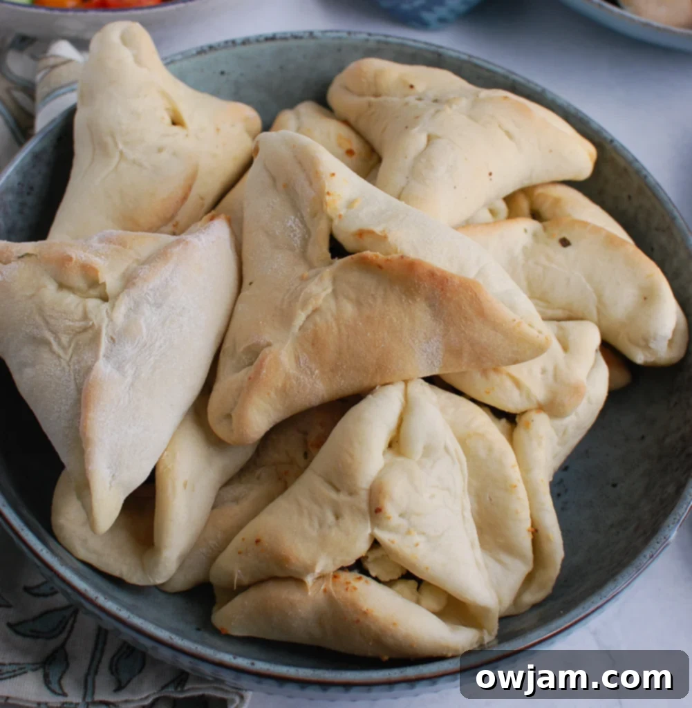Baked triangular pastries filled with a delicious spinach and cheese mixture, perfectly golden brown on a baking sheet.