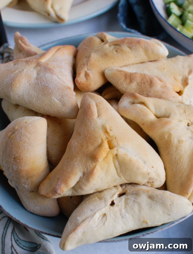 A close-up view of freshly baked Lebanese Meat Pies (Sfeeha) in a rustic bowl, highlighting their golden crust and the enticing texture of the spiced meat filling.