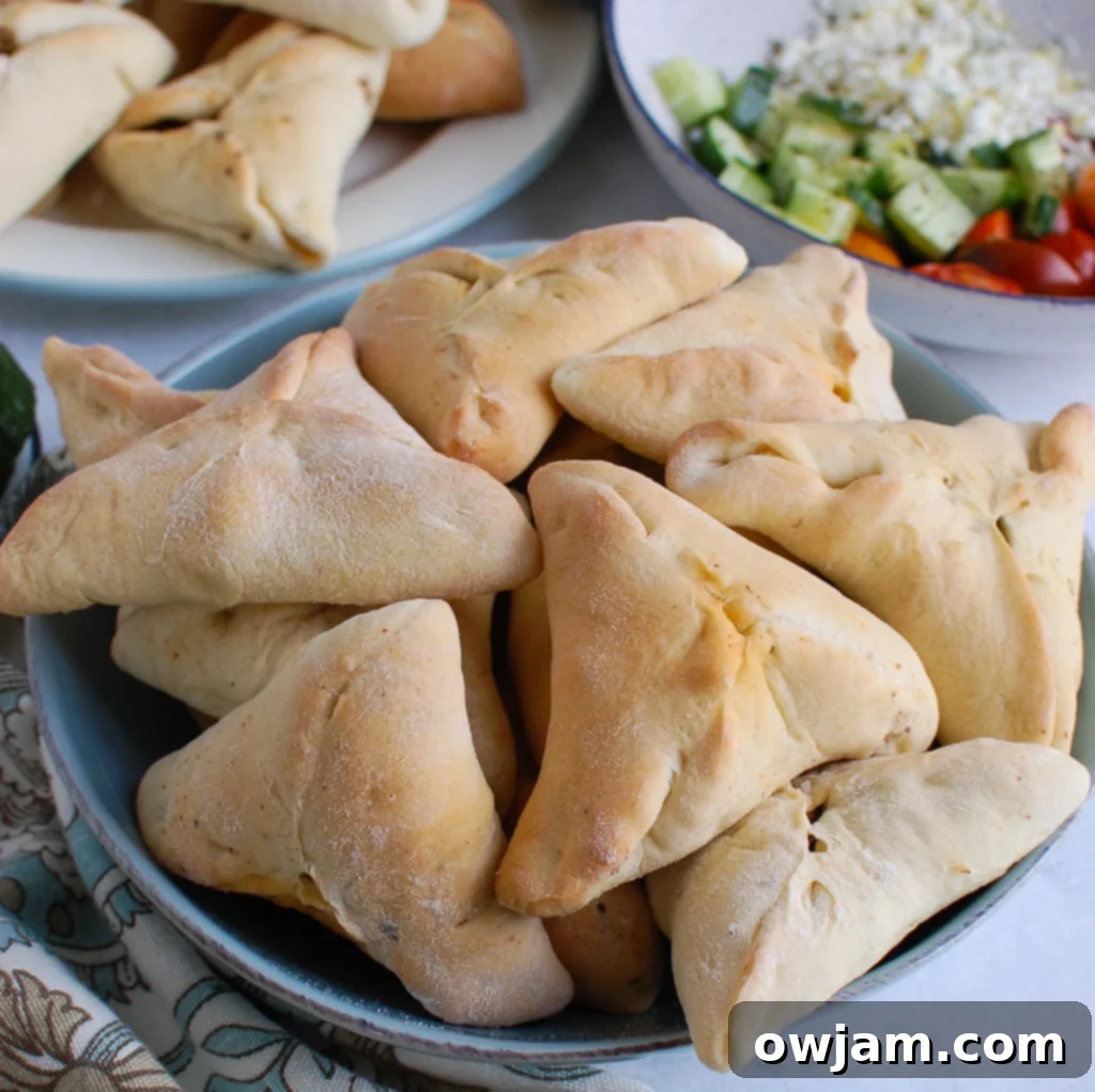 Freshly baked Lebanese Meat Pies (Sfeeha) served alongside a vibrant tabbouleh salad and cooling cucumber slices, creating a balanced and authentic Middle Eastern meal.