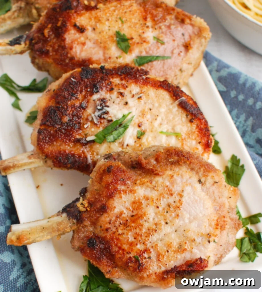 Perfect Oven-Baked Pork Chops 2 Crispy oven-baked pork chops with a golden breadcrumb crust on a white plate, garnished with fresh herbs, ready to serve.