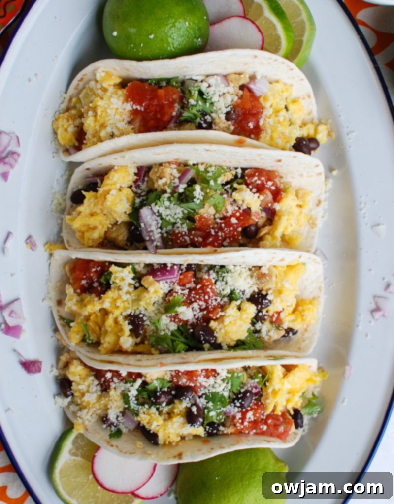Southwestern Sunrise Tacos 3 Close-up of Southwest Breakfast Egg Tacos on a white platter with scattered red onion, showing the vibrant ingredients.