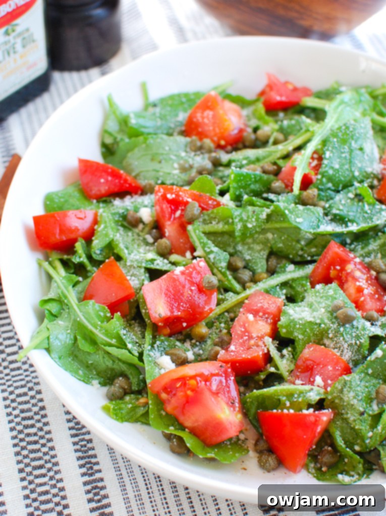 Arugula Salad with Capers in white bowl, close-up on ingredients