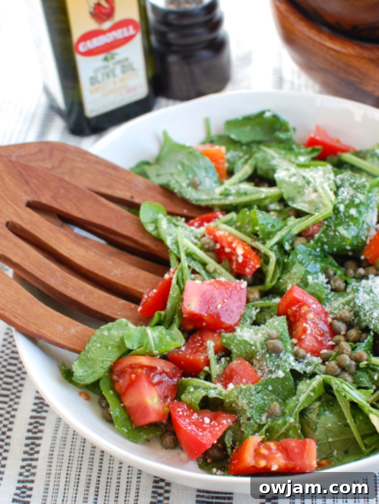Arugula Salad with Capers with wooden serving spoons, ready to be served