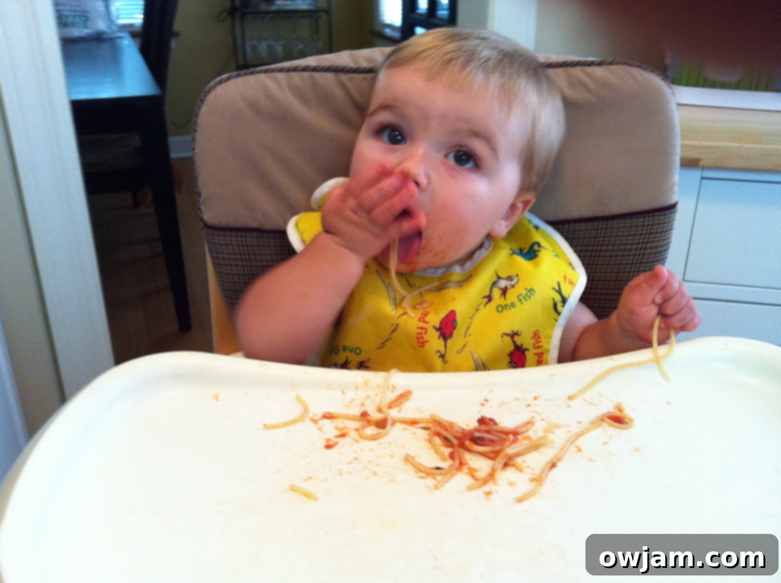Messy but happy baby with spaghetti all over his face, showcasing the joy of exploration