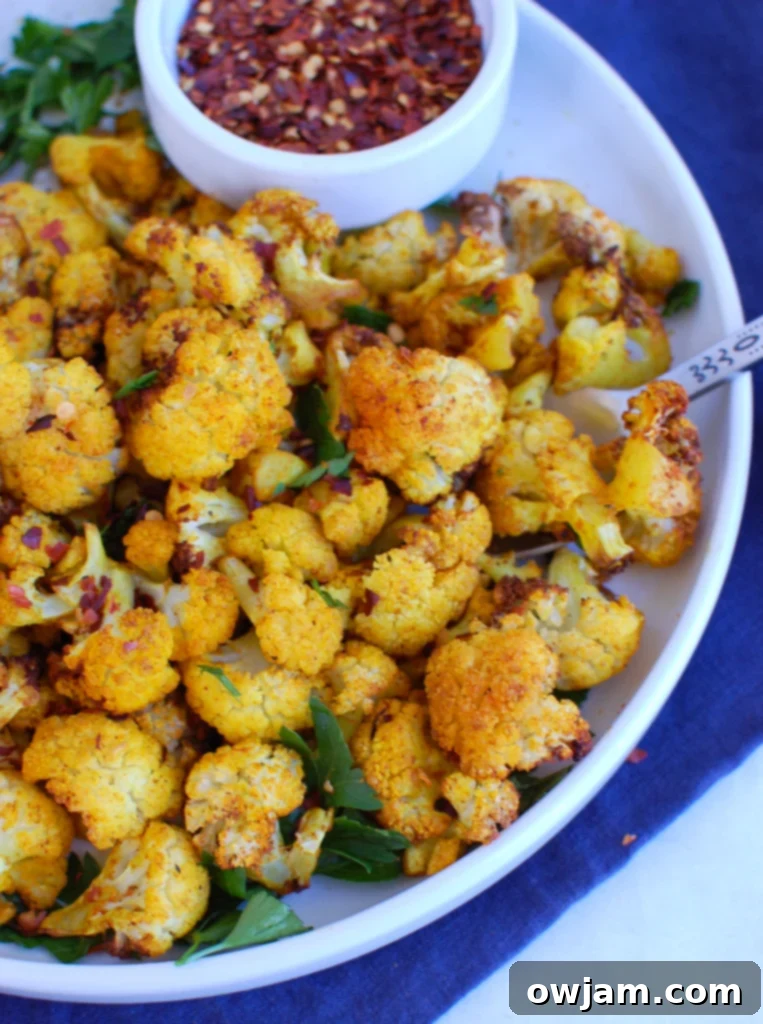 Crispy Air Fryer Cauliflower 2 Crispy Air Fryer Cauliflower on a white plate, garnished with fresh herbs, showcasing a delicious healthy side dish.