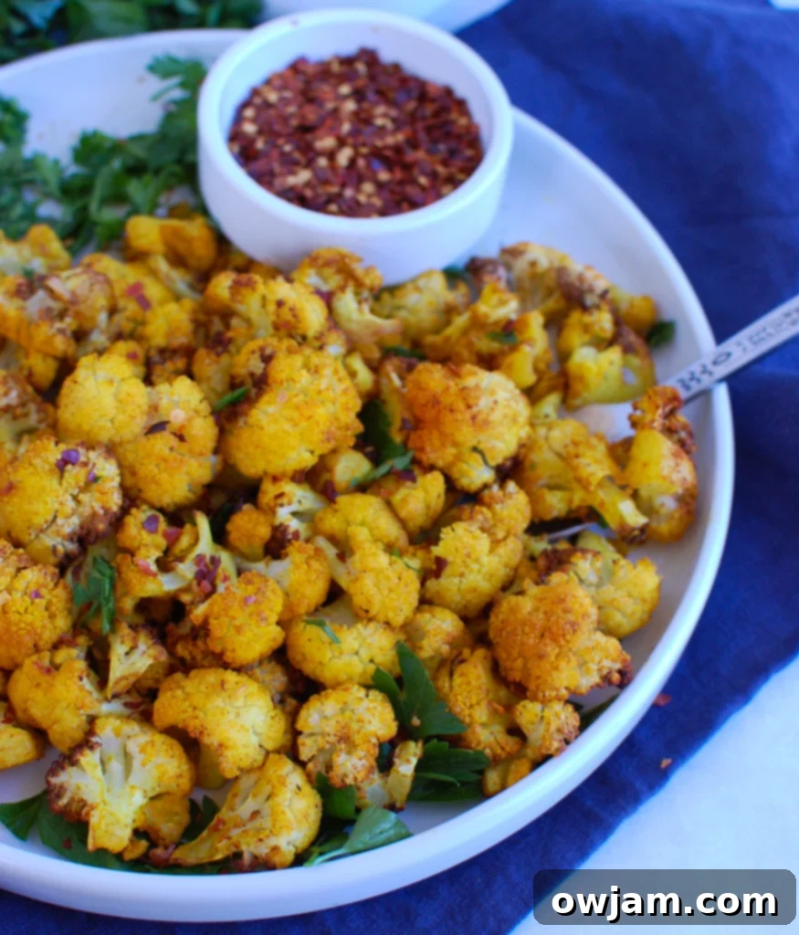 Crispy Air Fryer Cauliflower 5 Air Fryer Cauliflower on a round white plate with a side of dipping sauce, perfect for a healthy snack or side dish.