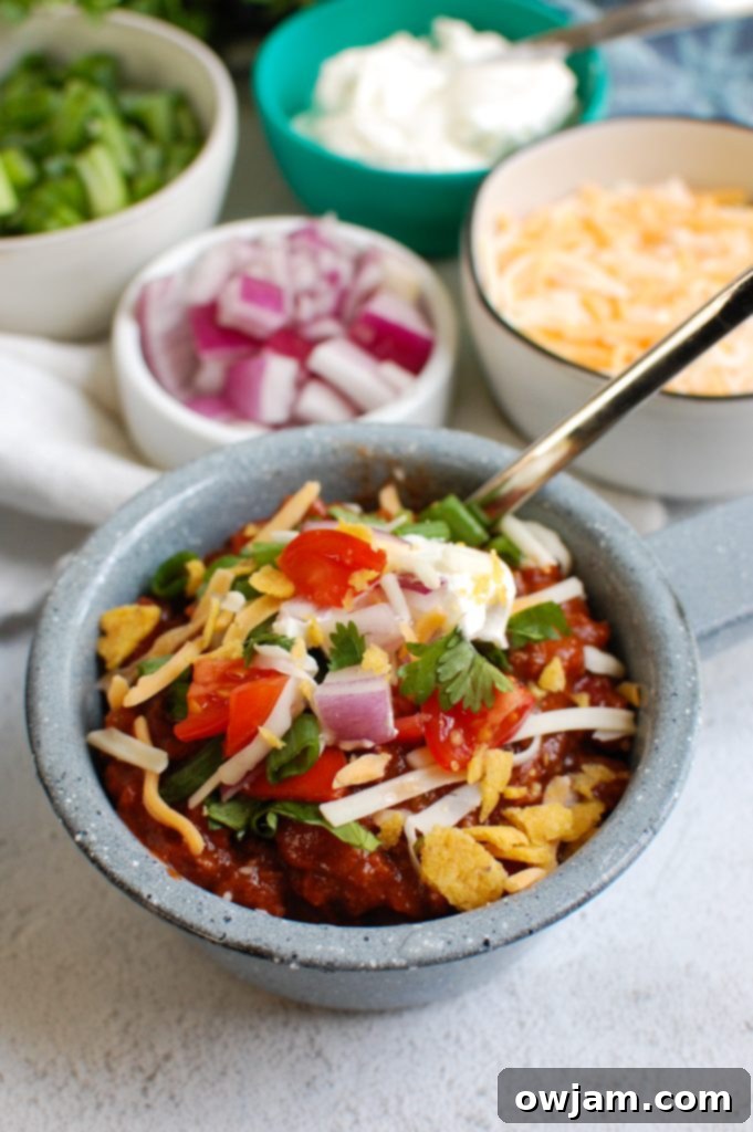Rich & Robust Beef Chili 2 Beef Chili Recipe in a blue bowl, garnished with sour cream and cilantro