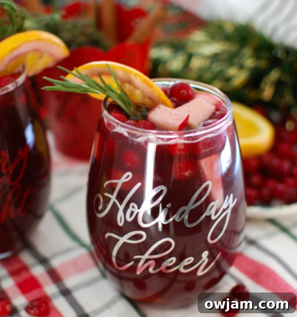 Merry Bright Sangria 2 Christmas Sangria garnished with fresh rosemary and cranberries in a glass pitcher
