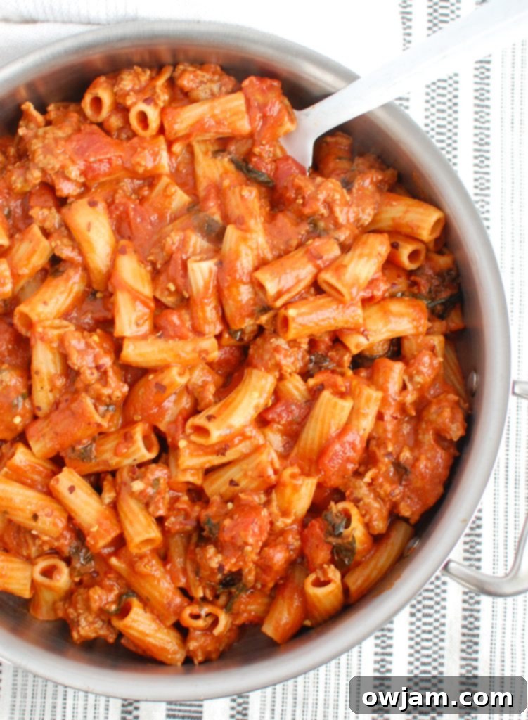 Zesty Sausage Pasta Supper 5 Overhead shot of Italian Sausage Pasta with a white serving spoon, ready to be dished out