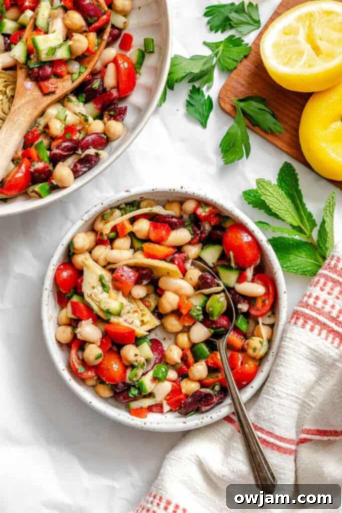 A large bowl of Mediterranean Three Bean Salad with a serving spoon, ready to be dished out.