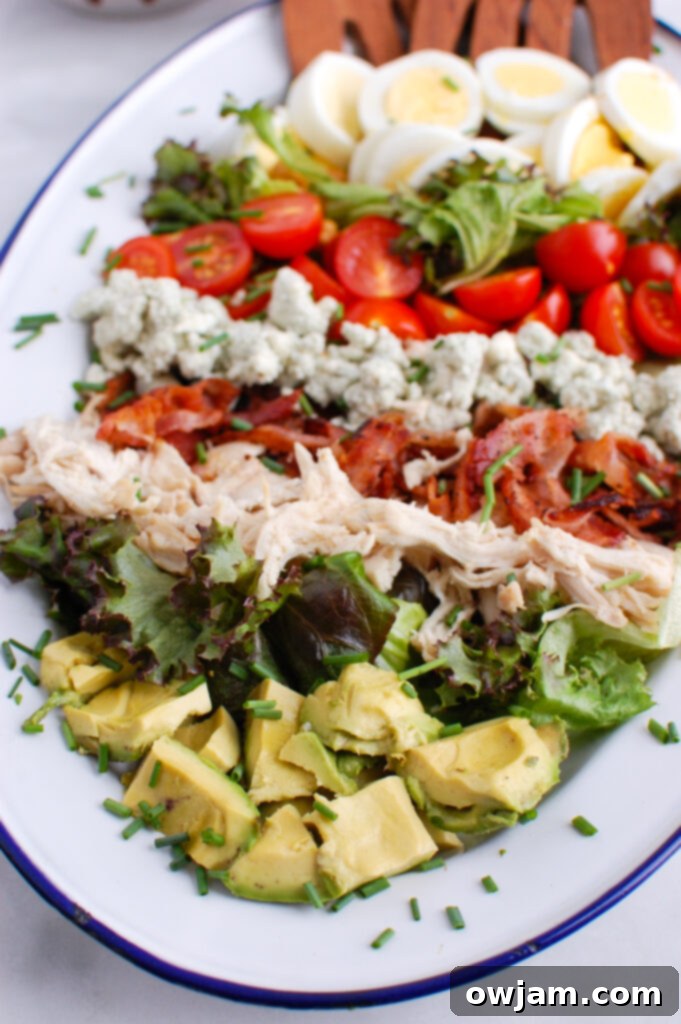 The Ultimate Cobb Salad 2 Beautifully arranged Cobb Salad on a large platter, showcasing layers of greens, tomatoes, avocado, eggs, blue cheese, chicken, and bacon.