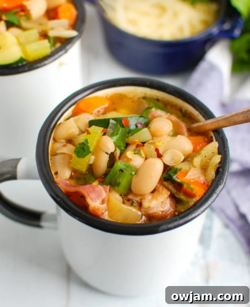 Rustic Tuscan Bean Soup 2 Tuscan Bean Soup in a white cup, garnished with fresh herbs, ready to be served as a comforting meal.