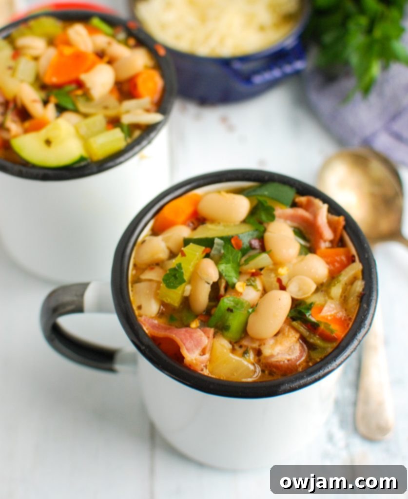 Rustic Tuscan Bean Soup 4 Two white mugs filled with hearty Tuscan Bean Soup, garnished with fresh parsley and a sprinkle of Parmesan.