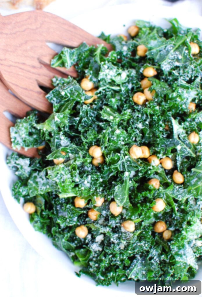 Elevated Kale Caesar 2 Vibrant Kale Caesar Salad served in a white bowl, garnished with Parmesan cheese and crispy chickpeas.