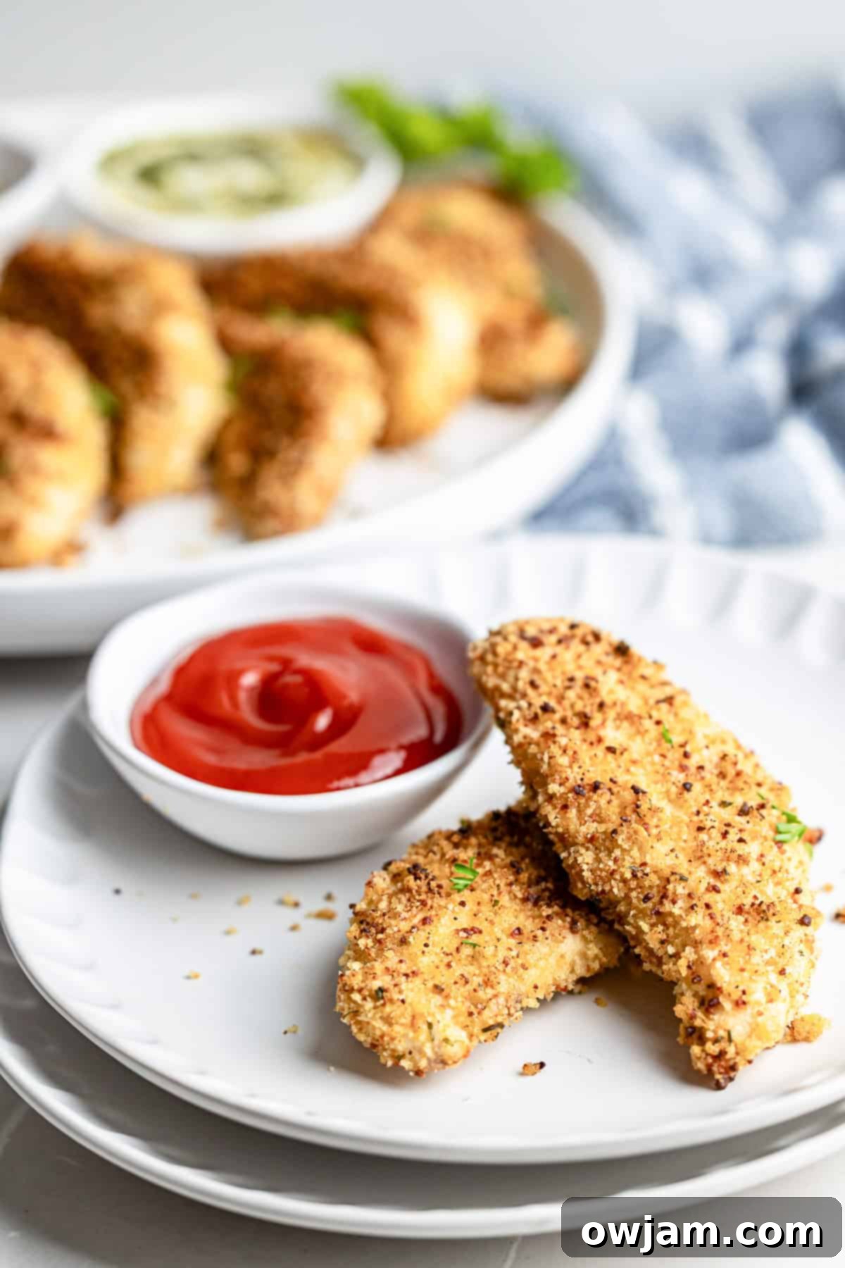Super Crispy Easy Baked Chicken Tenders 9 Plate of golden baked chicken tenders with an assortment of dipping sauces, ready to eat.