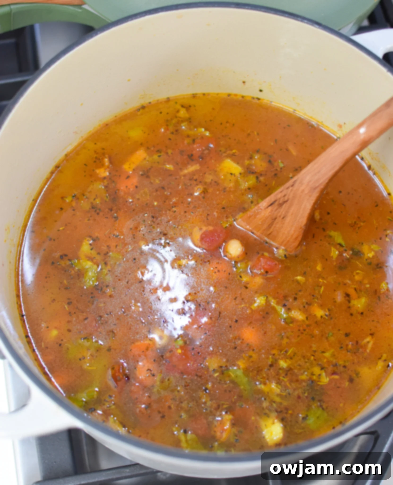 Garbanzo Soup Recipe simmering in a pot with a spoon.