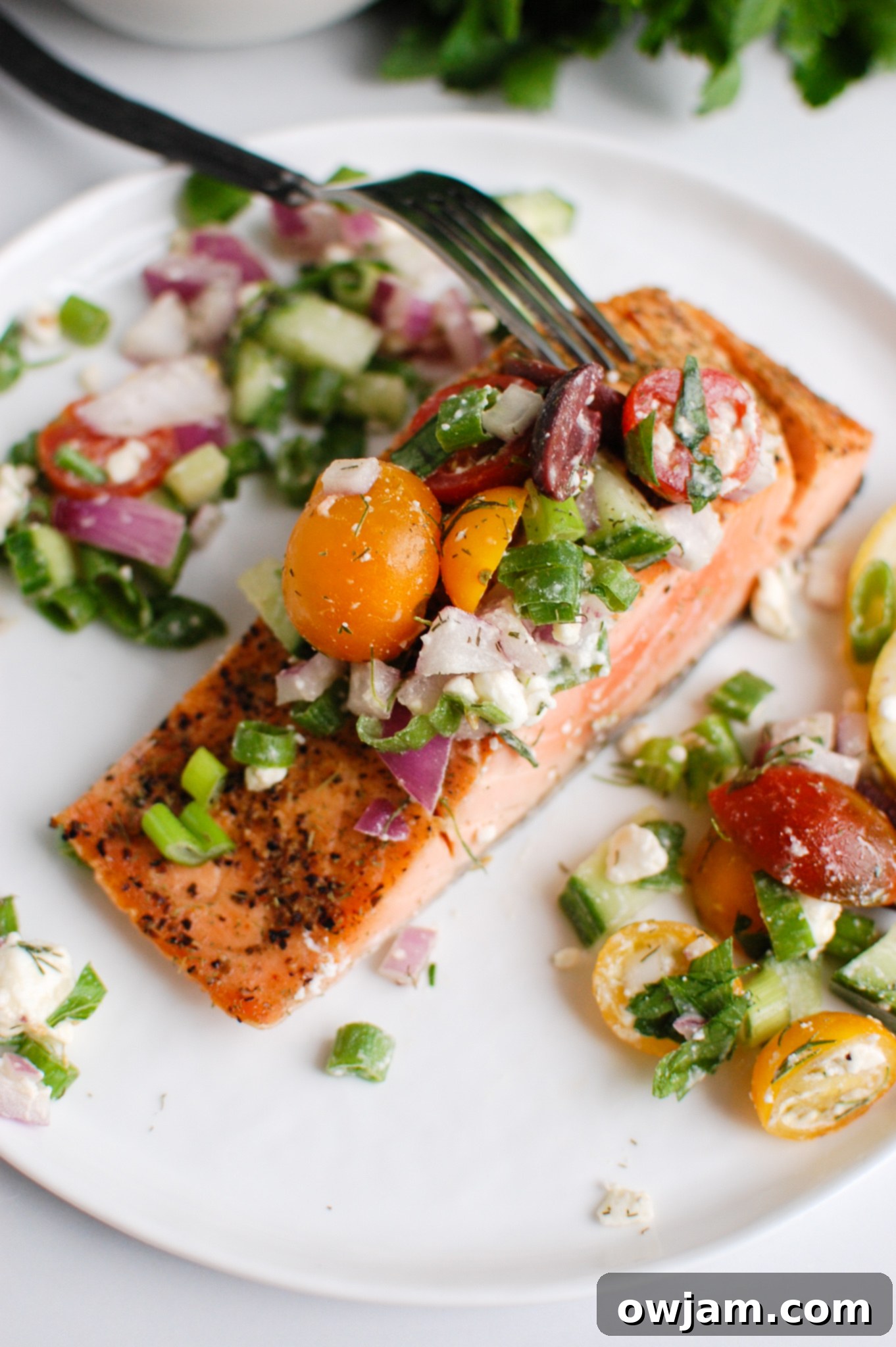 Your New Favorite Mediterranean Baked Salmon 3 a fork cutting into a filet of salmon.