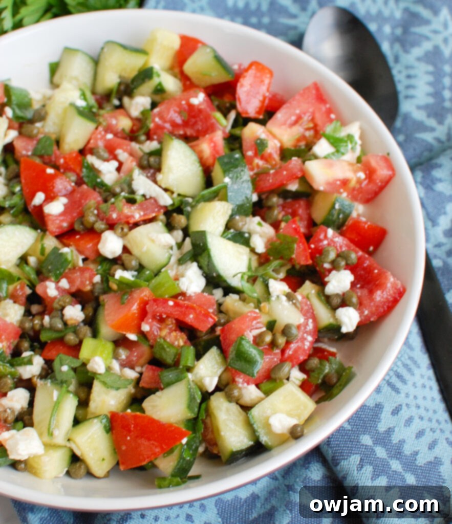 Vibrant Tomato Cucumber Caper Salad 4 Close-up of Tomato and Cucumber Salad with Capers, highlighting the crumbled feta cheese and fresh mint leaves.