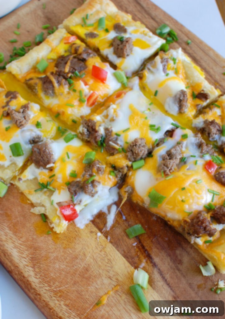 Turkey Sausage and Egg Puff Pastry Pizza on cutting board with a knife and fresh chives