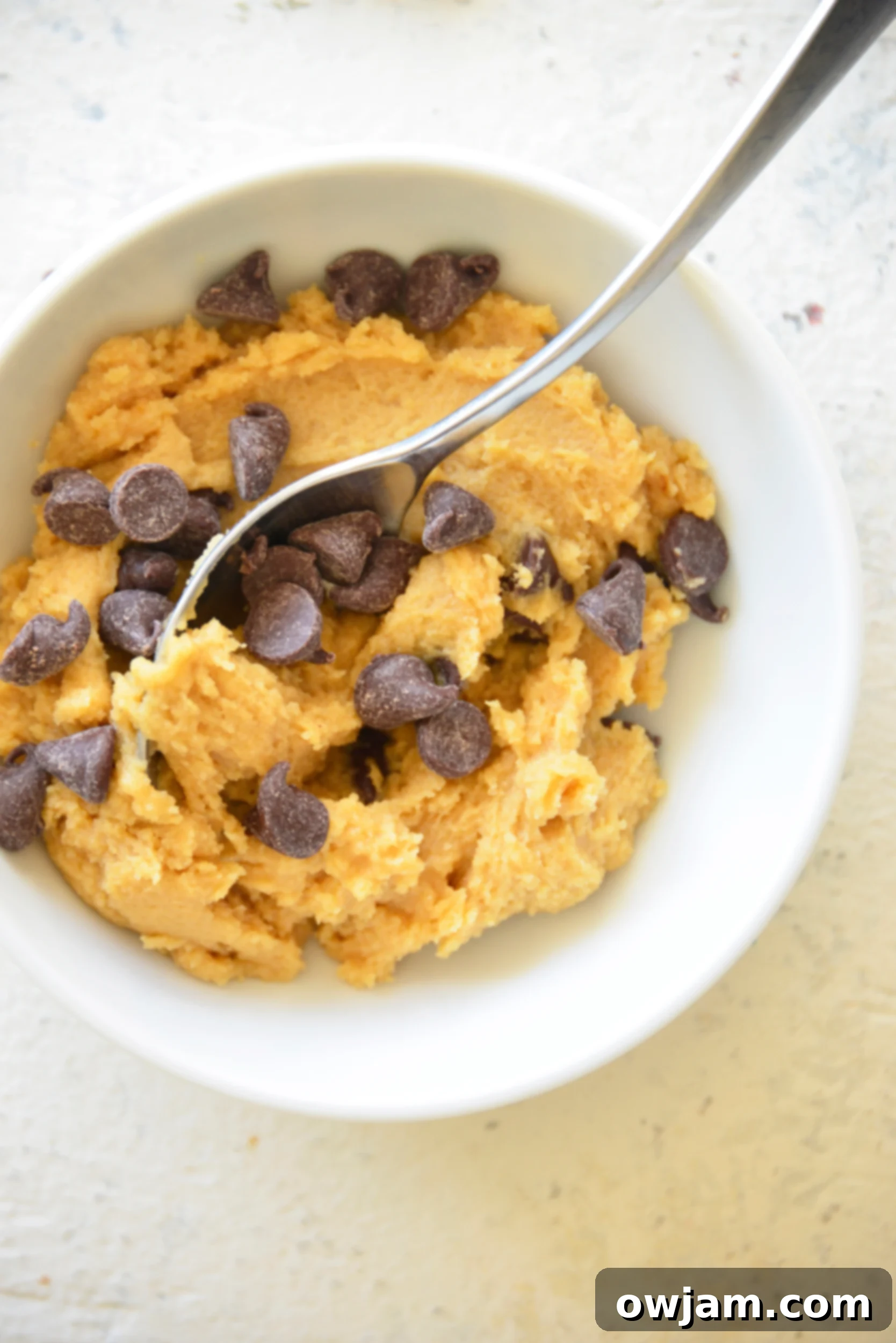 A small white bowl filled with delicious edible cookie dough for one, ready to be enjoyed.
