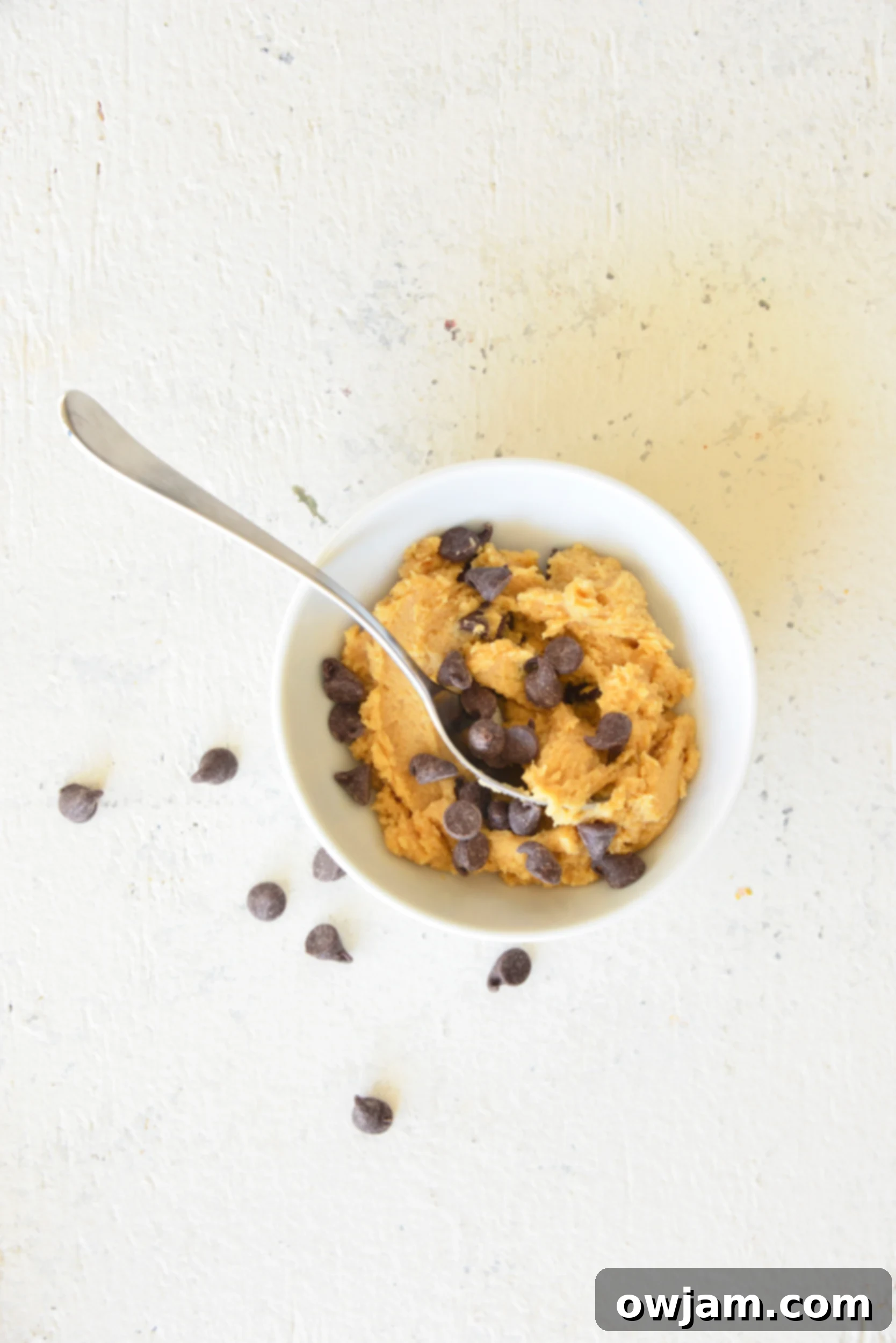A bowl of edible cookie dough for one, with a small scoop resting on the side, ready for serving.