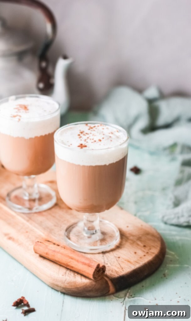 Instant Pot Chai Tea Latte served in a glass mug, garnished with cinnamon stick, on a rustic wooden board, emphasizing warmth and coziness.