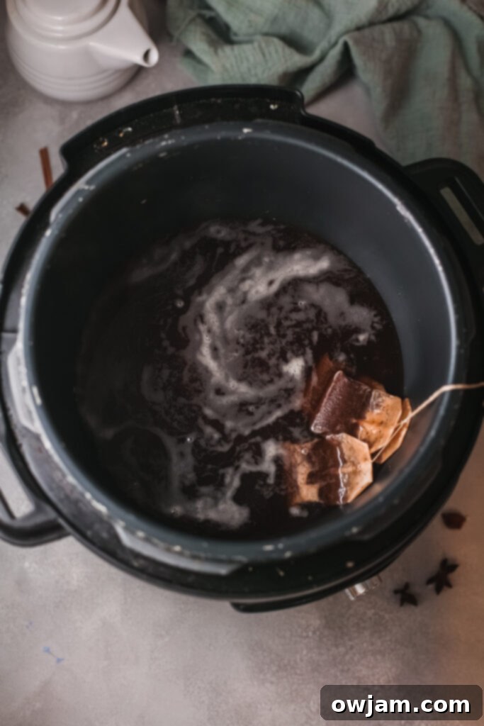 Instant Pot showing the tea bags steeping in hot water, illustrating the initial step of making chai latte.
