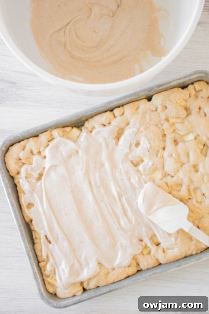 Pumpkin Spice Iced Apple Bars 7 Spreading creamy Pumpkin Pie Spice Icing onto baked Apple Bars using a spatula.