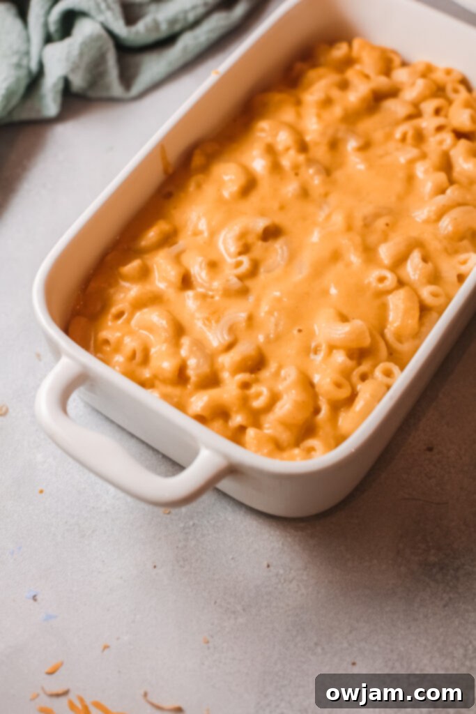 Creamy Pumpkin Mac and Cheese 7 Pumpkin Mac and Cheese with shredded cheese being mixed in, creating a rich and gooey texture.