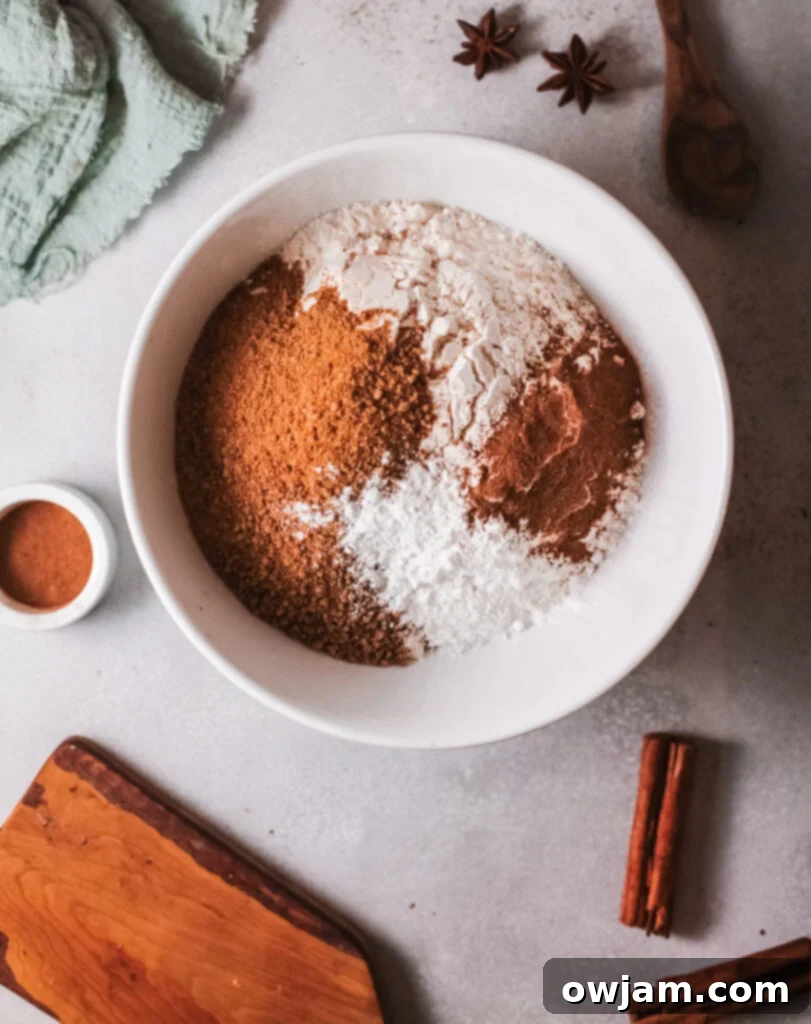 Bowl with a mixture of dry ingredients: flour, brown sugar, baking powder, pumpkin pie spice, and cinnamon, ready to be combined.