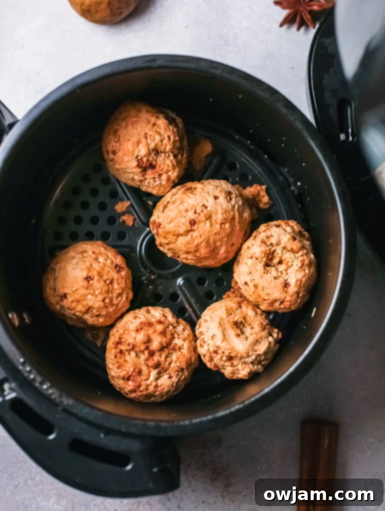 Pumpkin donut holes nestled in an air fryer basket, lightly sprayed with oil and ready for cooking.