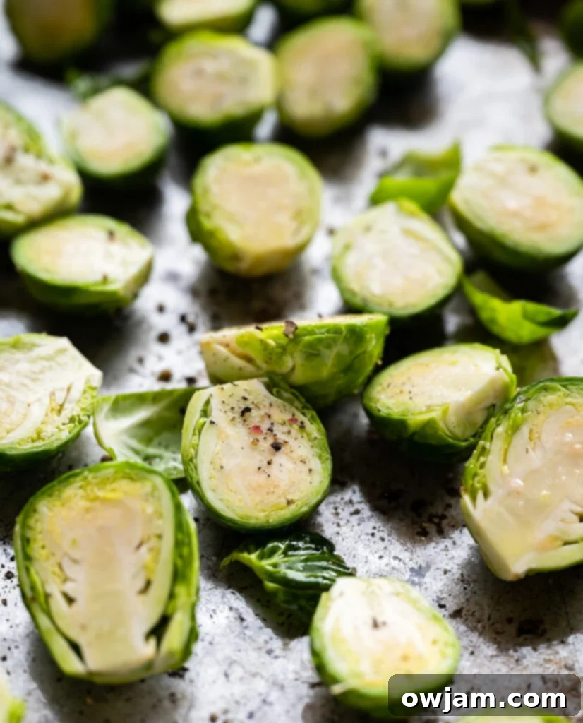 Caramelized Balsamic Brussels Sprouts 5 Halved Brussels sprouts coated in olive oil and seasoning, spread out on a baking sheet, ready for roasting.