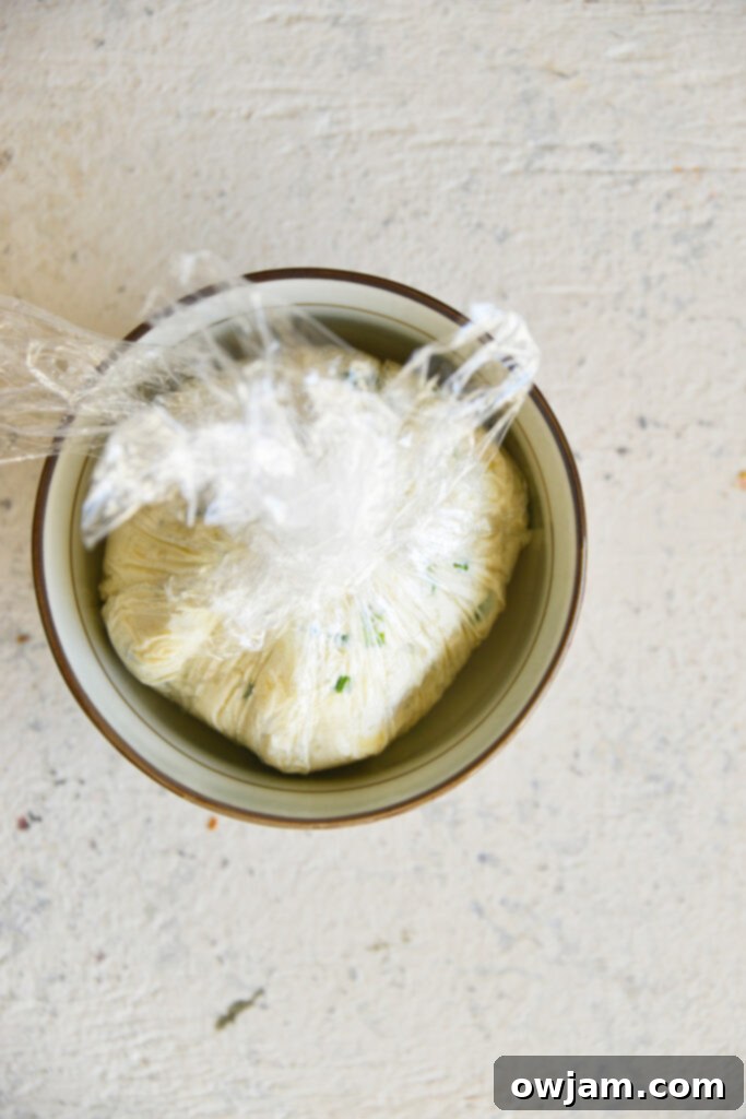Whip Up a Crowd-Pleasing Cheese Ball 7 Cheese ball mixture wrapped in plastic wrap in a bowl